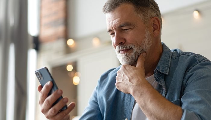 Homem usando aparelho auditivo G Series AI enquanto olha o celular